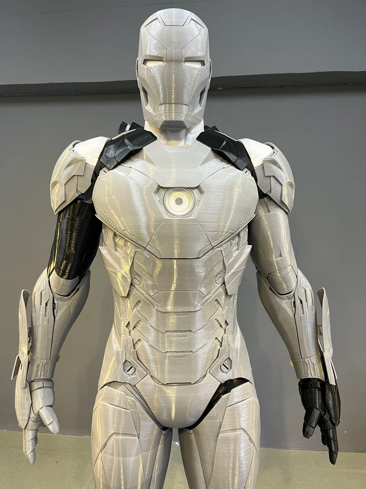 Photo réelle d’une armure Iron Man MK46 brute en PLA clair, du casque aux cuisses, avec les strates d’impression visibles.